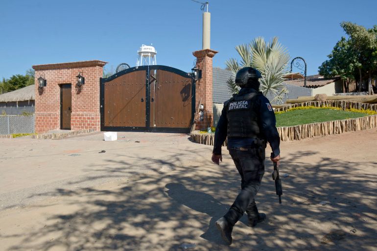 An armed police officer walks past the mansion where Ovidio Guzman was arrested in January