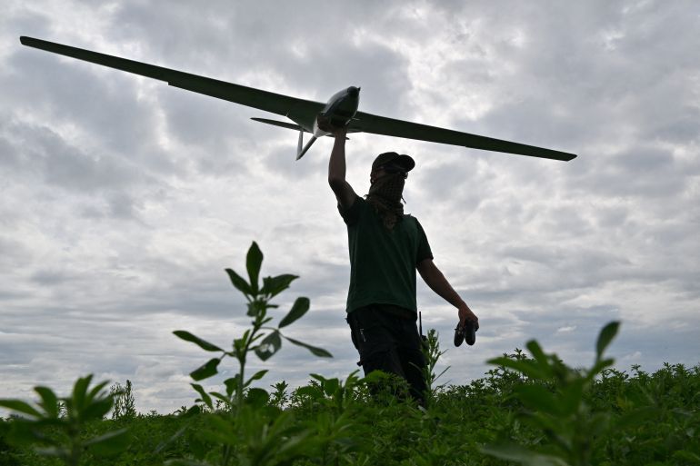 An operator carries a reusable airstrike drone called Punisher made by the Ukrainian company UA Dynamics during a test in Kyiv region on August 11, 2023, amid Russian invasion in Ukraine. (Photo by Sergei SUPINSKY / AFP)