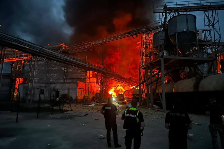 Ukrainian law enforcement officers stand next to the burning industrial facility following a Russian air attack in the Poltava region, Ukraine, in August 2023