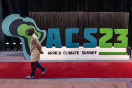 A worker walks past an Africa Climate Summit logo during preparations ahead of the Africa Climate Summit 2023 at the Kenyatta International Convention Centre in Nairobi, Kenya on September 2, 2023. - The inaugural Africa Climate Summit will be held in Nairobi and aims to address the increasing exposure to climate change and its associated costs, both globally and particularly in Africa. (Photo by Luis Tato / AFP)