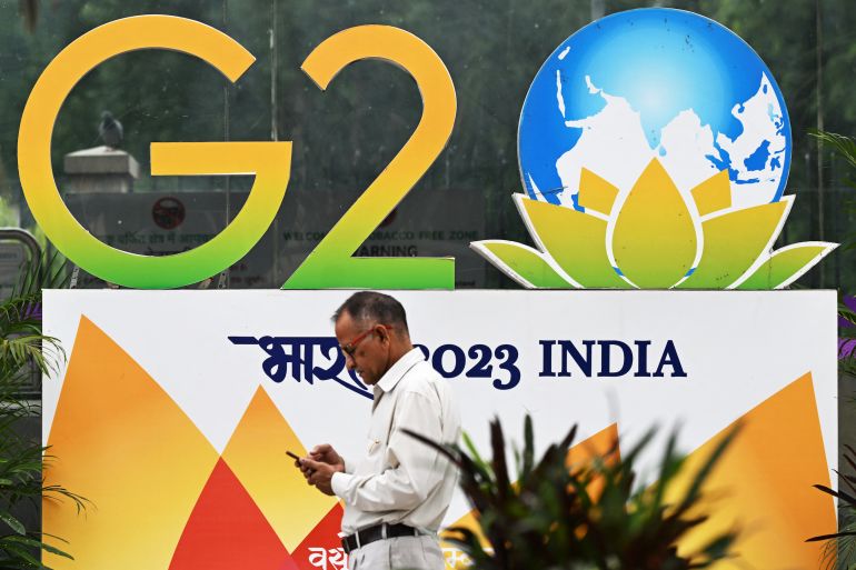 A pedestrian walks past a G20 summit logo installed along a street in New Delhi on September 6, 2023.