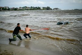 People try to pull out a car submerged in the sea at Arapia camping site near Tsarevo along the Bulgarian Black sea coast
