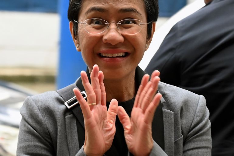 Maria Ressa with her hands in front of her. She's smiling.
