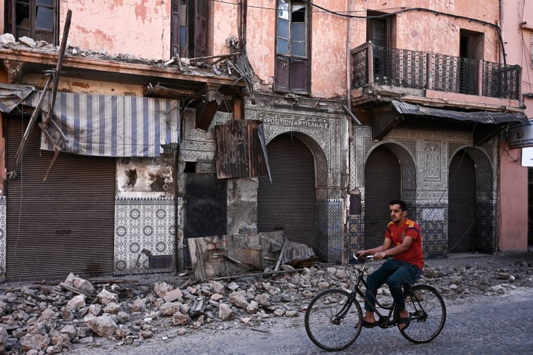 A man rides a bicycle past an earthquake-damaged building in the old quarters of Marrakesh on September 10, 2023.