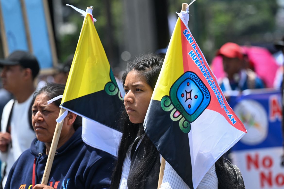 An Indigenous protester holds two flags as demonstrators march through Guatemala City on September 18.