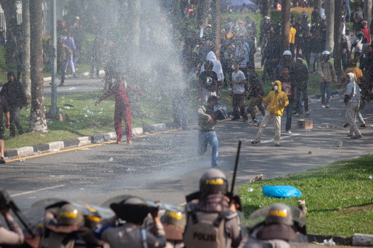 Protesters face off with police in riot gear amid clouds of tear gas,