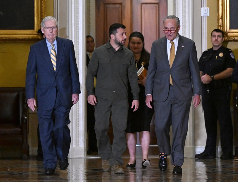 Ukrainian President Volodymyr Zelensky (C), accompanied by US Senate Majority Leader Chuck Schumer (2nd R) and Senate Minority Leader Mitch McConnell (L), arrives to meet with US Senators in the Old Senate Chamber, at the US Capitol in Washington