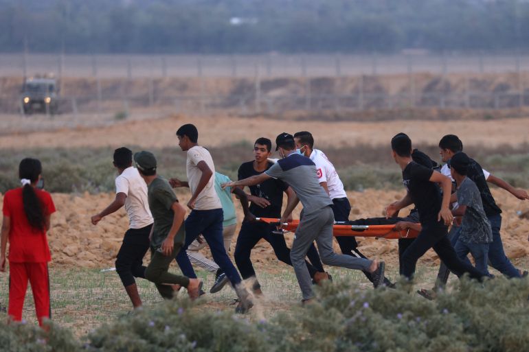 Palestinian demonstrators and medics evacuate a fellow demonstrator during clashes with Israeli soldiers near the Israel-Gaza border fence
