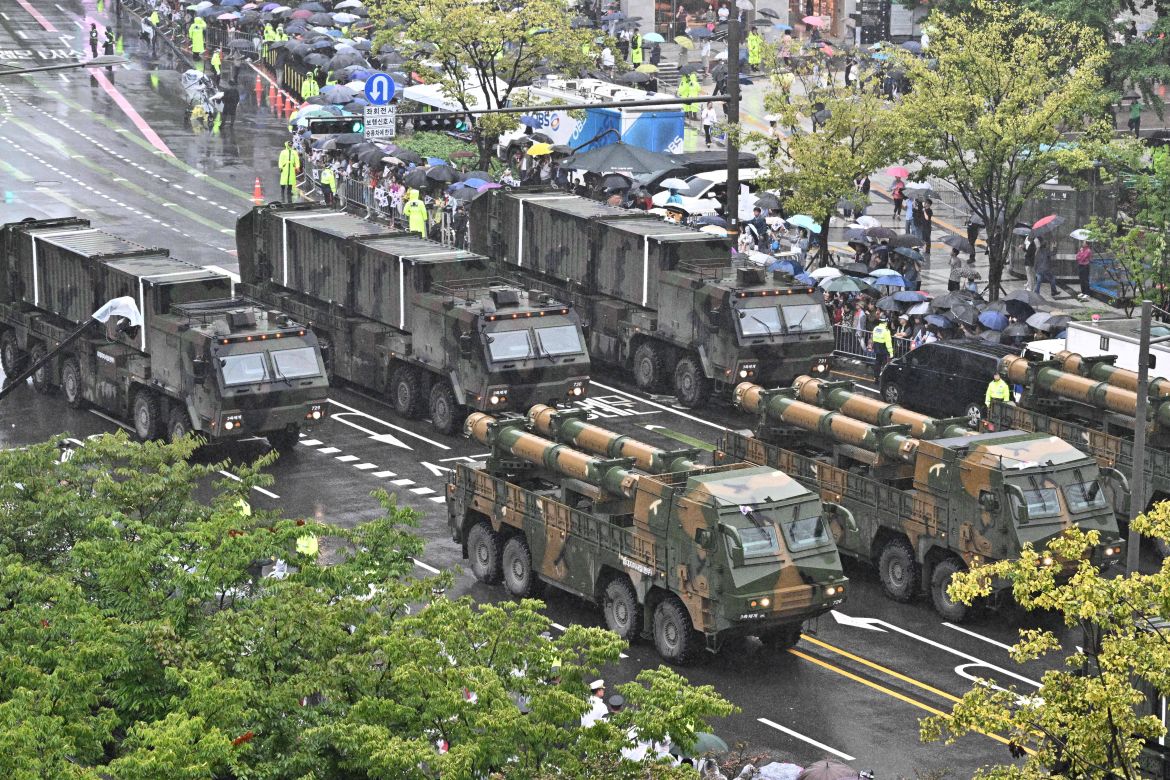 Hyunmoo-3 vehicles join the military parade, They are seen through the trees.