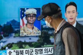 (FILES) In this photo taken in Seoul on August 16, 2023, a man walks past a television showing a news broadcast featuring a photo of US soldier Travis King (C), who ran across the border into North Korea while part of a tour group visiting the Demilitarized Zone on South Korea's border on July 18. - North Korea has decided to expel US soldier Travis King, who was detained after crossing the border from the South in July, the KCNA state news agency said on September 27. (Photo by Anthony WALLACE / AFP)