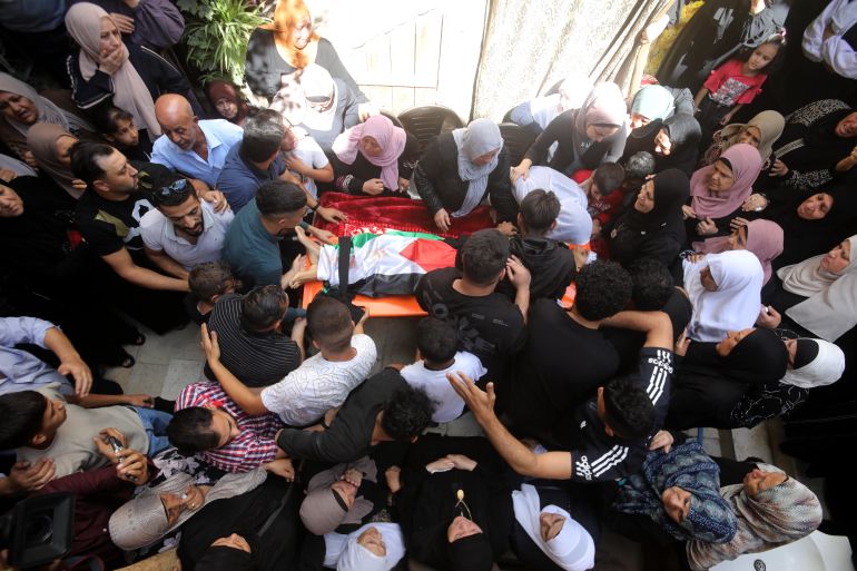 Mourners gather around the body of Milad al-Raee,