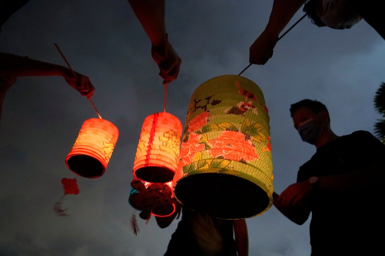 People lighting lanterns for the Mid-Autumn festival.