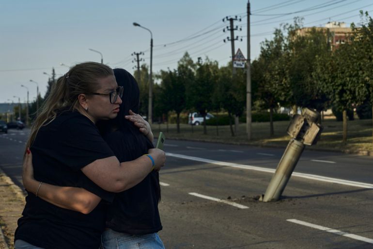 Local residents react near a fragment of the Russian rocket after an attack in Kramatorsk, Donetsk region, Ukraine, Saturday, Sept. 2, 2023. (AP Photo/Libkos)