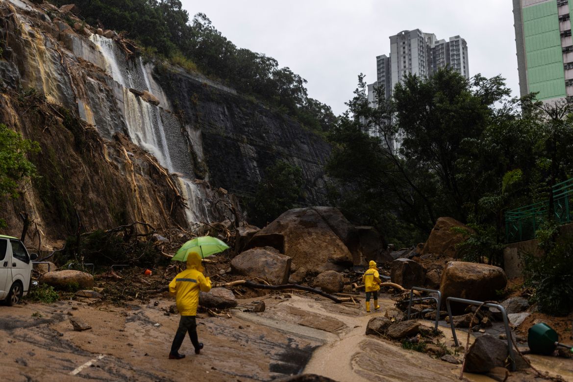 Workers walk through a landslide following heavy rainstorms in Hong Kong