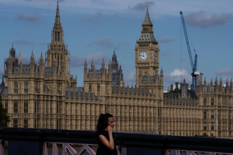 A woman walks past the Houses of Parliament in London