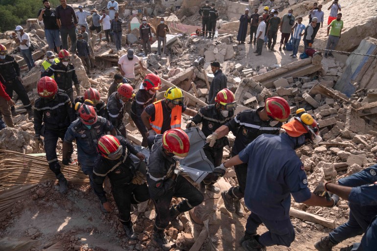 Uma equipe de resgate recupera o corpo de uma mulher morta no terremoto, na cidade de Imi N'tala, nos arredores de Marrakech, Marrocos, terça-feira, 12 de setembro de 2023. (AP Photo/Mosa'ab Elshamy)