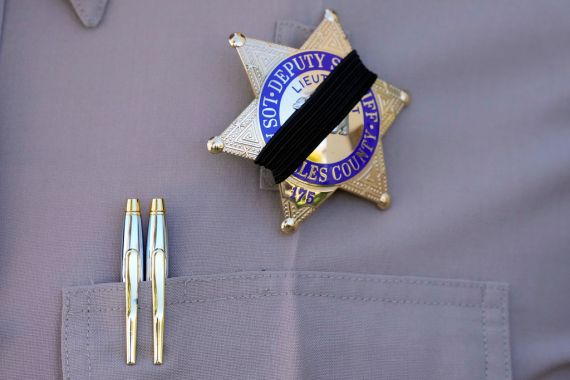 A member of the Los Angeles County Sheriff's department wears a black band over his badge in honor of deputy Ryan Clinkunbroomer outside of the Palmdale Sheriff's Station Monday, Sept. 18, 2023, in Palmdale, Calif. Deputy Clinkunbroomer was shot and killed while sitting in his patrol car Saturday evening in Palmdale. (AP Photo/Marcio Jose Sanchez)