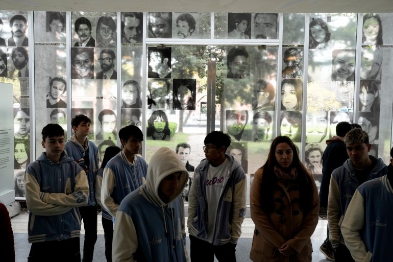 Photos of people who disappeared during the Argentine dictatorship (1976-1983) are displayed on the wall where students walk through the ESMA Museum and Site of Memory on the day the museum was declared a UNESCO World Heritage Site in Buenos Aires, Argentina, Tuesday September 7, 19, 2023. 