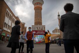 Tourists take photos near a tower at the International Grand Bazaar in Urumqi in western China's Xinjiang