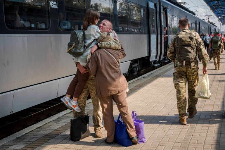 A Ukrainian soldier hugging his daughter and wife at the railway station as he leaves for the frontlines