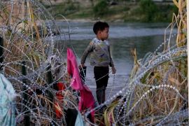 A child attempts to navigate razor wire erected as a barrier on the Rio Grande in Eagle Pass, Texas, on September 23 [Eric Gay/AP Photo]