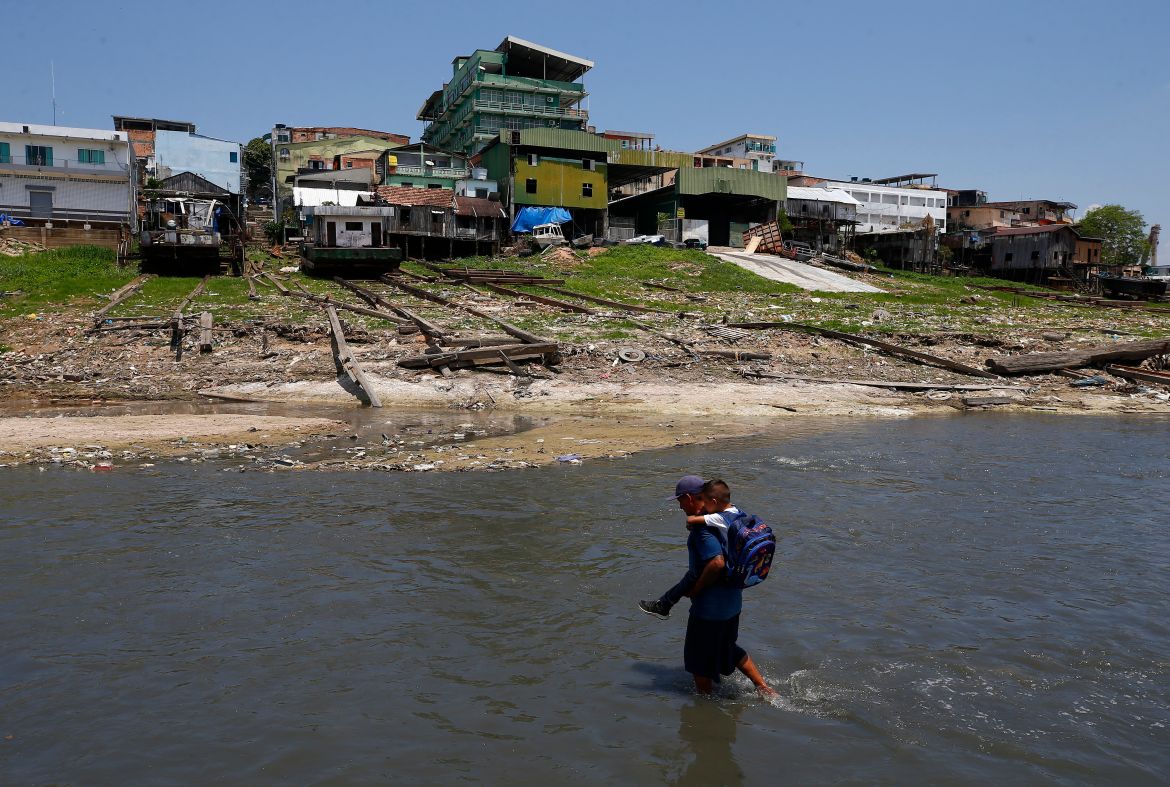 Uanderson Marinho de Souza, 40, carries his son to school across the much-diminished Negro river