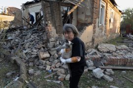 Injured Ludmila Ivanchuk, 61, holds her cat in front of her house which was damaged by a Russian rocket attack in Kostiantynivka, Donetsk region [Alex Babenko/AP Photo]