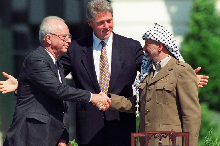 Rabin and Araft shake hands as Clinton stands with his arms outstretched between them