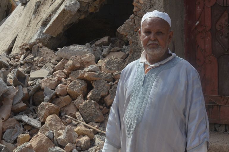 A man stands outside the rubble of his former home.