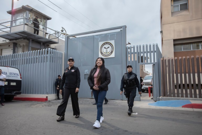 Alina Narciso walks with two police officers away from the gate of La Mesa prison and onto the street.