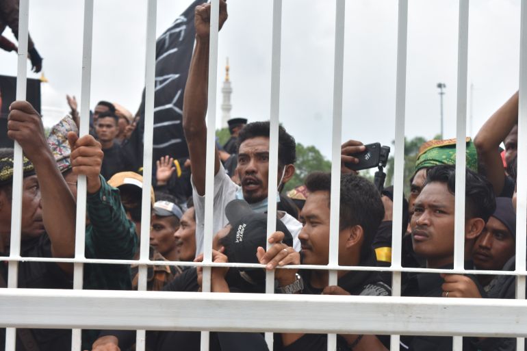 Protesters in Batam pushing up against a gate