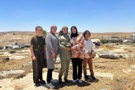 Five young girls who just finished playing on Khirbet Susiya’s playground stand triumphantly in front of their village.