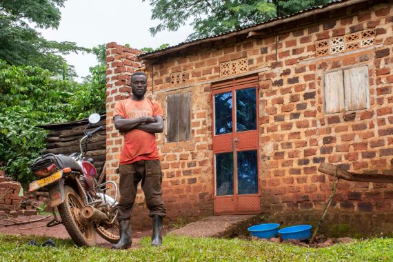 Joachim Kyibabu stands outside his home in Busamba village, Wakiso, Uganda