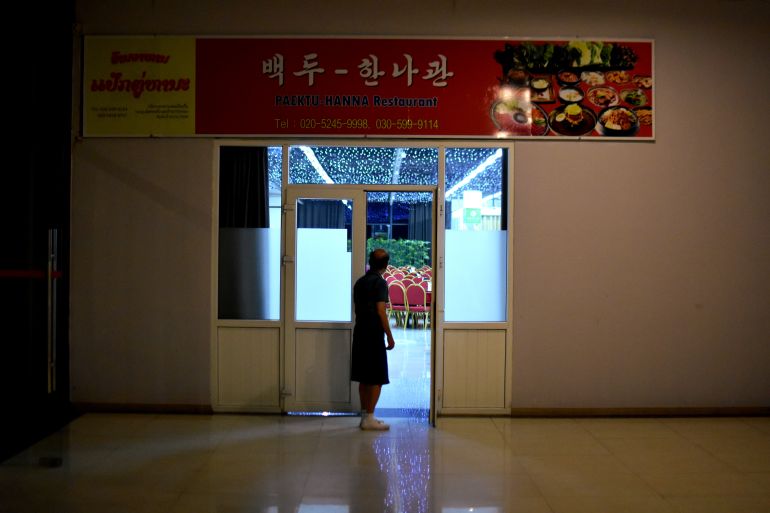 Birisi Vientiane'deki boş Paektu Kuzey Kore restoranına bakıyor.  Işıkların hepsi açık ama çok sessiz.