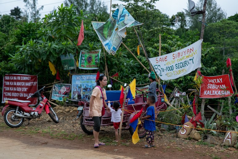 A protest camp set up in Sibuyan against the mine. There are banners calling for an end to mining. A family is walking past