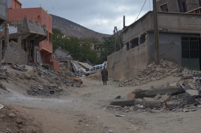 A man walks through a town street lined with rubble, after one of the buildings crumbled from the quake.