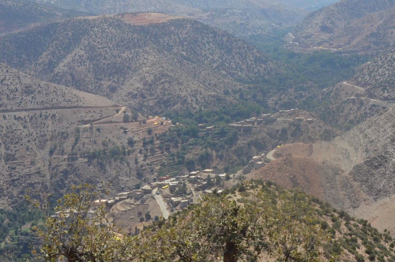 An aerial view of the Atlas Mountains, with towns and tents below.