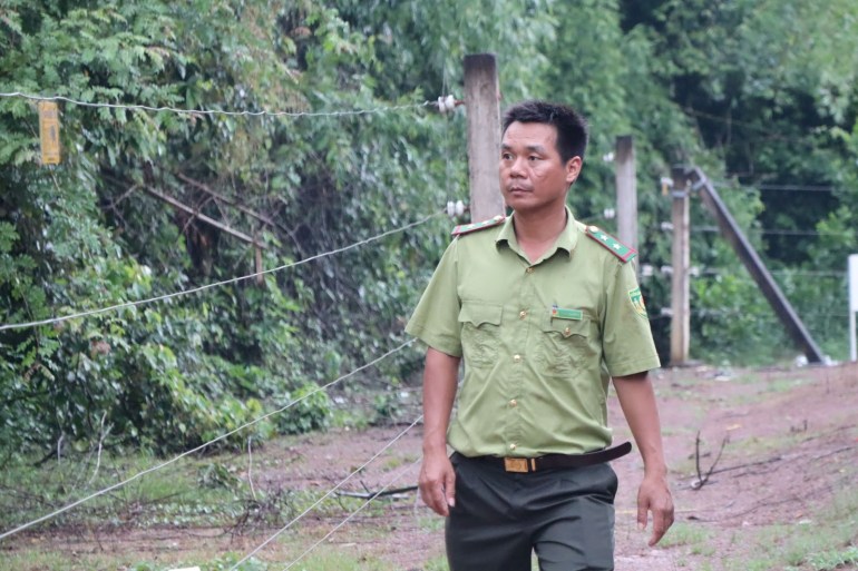 Tran Dai Nang, a forest ranger walks by part of the electric fence used to keep elephants in and humans out in Dong Nai Culture And Nature Reserve. [Sen Nguyen/Al Jazeera]