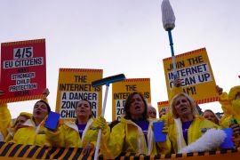 Protesters in hazmat suits holding placards and mops demand action from the EU on proliferation of childhood sexual abuse materials online