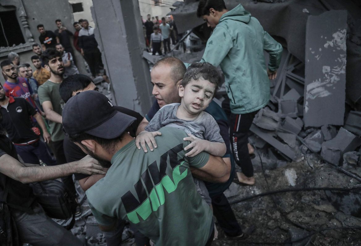 A child is recovered from the rubble of a residential building leveled in an Israeli airstrike, in Khan Younis
