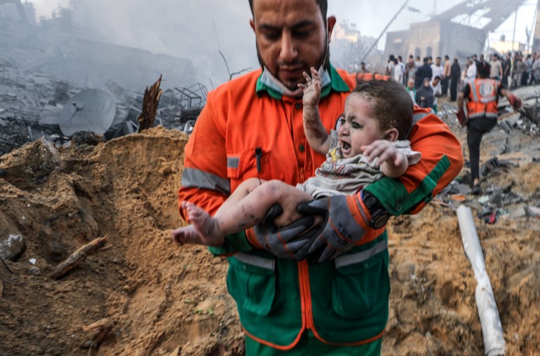   Un Palestinien porte un bébé blessé qu'il a récupéré dans les décombres d'une zone détruite suite aux frappes aériennes israéliennes 
