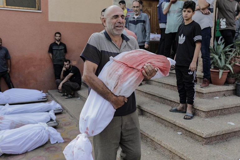 Relatives of Palestinians killed during the ongoing Israeli-Hamas conflict escalation mourn next to their bodies at the Nasser Hospital in Khan Yunis, 