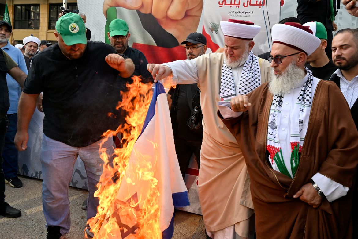 People burn an Israeli flag during a protest of the Hamas movement and Islamic Group in solidarity with the Palestinian people, amid the ongoing conflict between Israel and Hamas in the Gaza Strip, in downtown Beirut, Lebanon