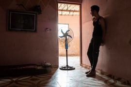 A boy standing near a fan