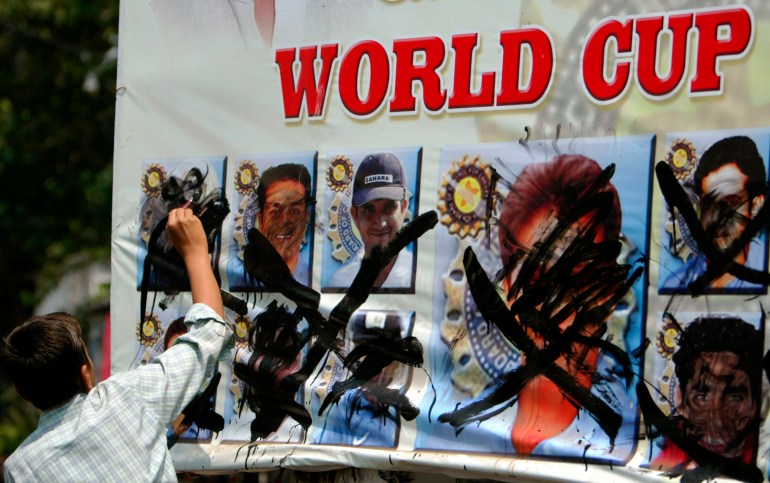 A cricket fan blackens a poster displaying the faces of Indian cricket team players in Mumbai March 24, 2007. Hundreds of cricket fans across India burnt effigies, defaced posters and held mock funeral processions of the national team, a day after their defeat to Sri Lanka in the World Cup match in the Caribbean. REUTERS/Punit Paranjpe (INDIA)