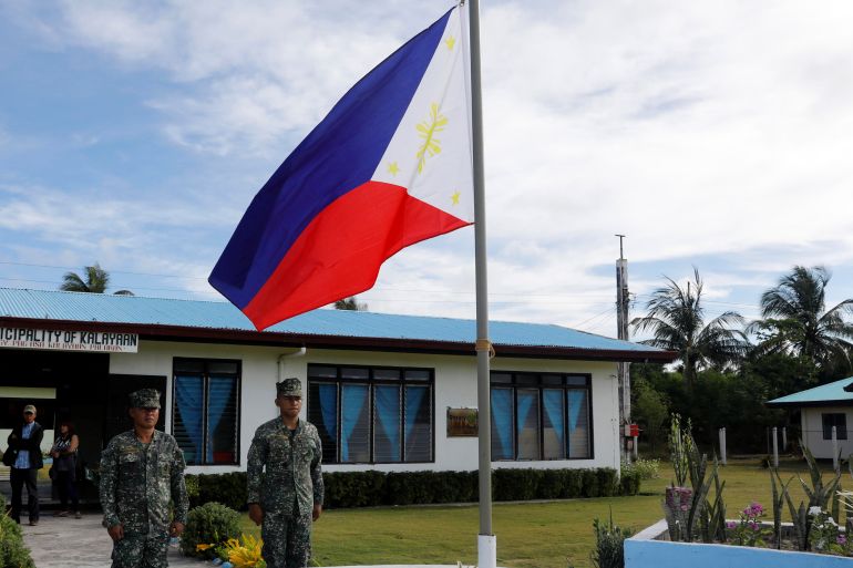 Philippines soldiers standing to attention in front of their country's flag at Thitu island in the Spratlys.