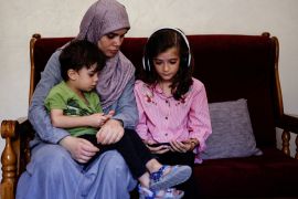 Palestinian mother Sajeda Abdu and her children Youssef and Juman look at a mobile phone