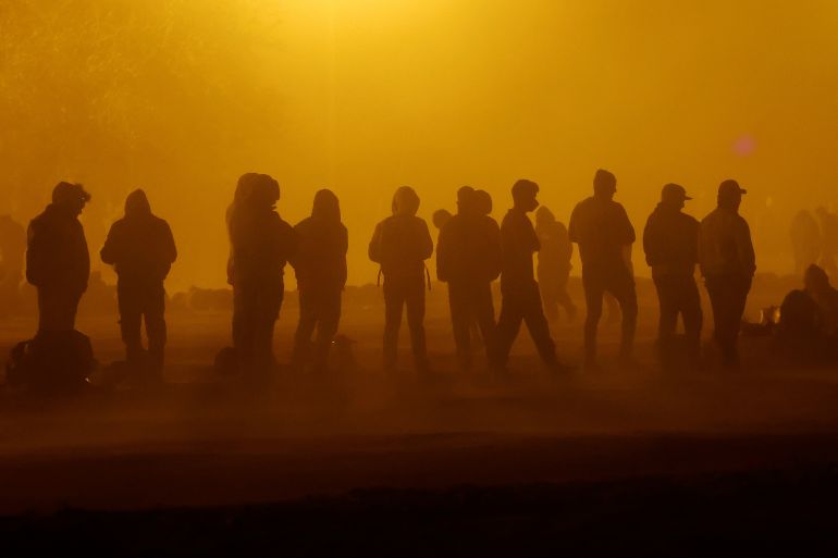 Migrants stand near the border wall during a sandstorm after having crossed the US-Mexico border to turn themselves in to U.S. Border Patrol agents, as the U.S. prepares to lift COVID-19 era Title 42 restrictions that have blocked migrants at the border from seeking asylum since 2020, in El Paso, Texas, U.S., May 10, 2023. REUTERS/Jose Luis Gonzalez