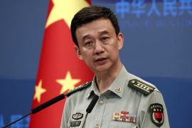 China's Ministry of Defence spokesperson Wu Qian. He is wearing a uniform and standing in front of a Chinese flag