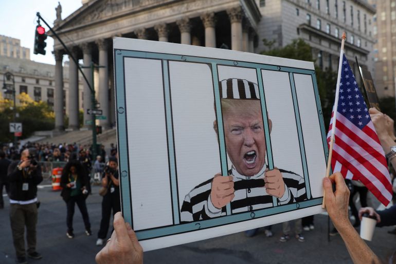 An anti-Trump demonstrator holds up a sign featuring an image of former U.S. President Donald Trump